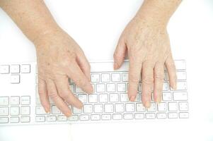 mãos do a velho fêmea digitando em a teclado, isolado em branco, fechar-se. foto