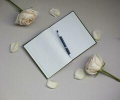 em branco caderno com Lugar, colocar para texto e rosa flores em cinzento fundo. Visão a partir de acima foto