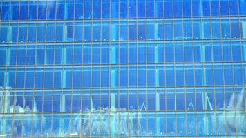 estrutural vidro parede refletindo azul céu. abstrato moderno arquitetura fragmento. vidro construção com transparente fachada do a construção e azul céu. contemporâneo arquitetônico fundo. foto