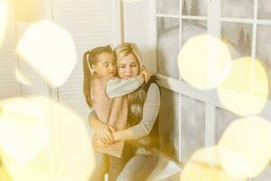 mãe e filha estão sentado de a janela dentro a crianças quarto foto