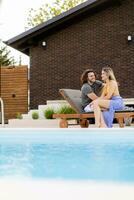 jovem casal relaxante de a natação piscina dentro a casa quintal foto