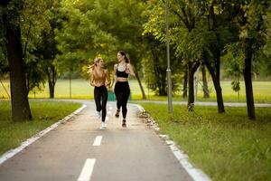 dois bonita jovem mulheres corrida em a faixa dentro a parque foto