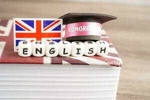 Inglês livro com graduado chapéu, Aprendendo e tutorial para estrangeiro. foto
