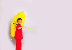 Garoto moda uma estilo chinês camisa segurando uma amarelo guarda-chuva poses para uma foto atirar.