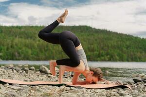 Treinamento dentro natureza, melhora pilates e alongamento. confiante e harmonia dentro uma saudável humano corpo. a treinador fazendo a ioga asana exercício, usa uma esteira. foto