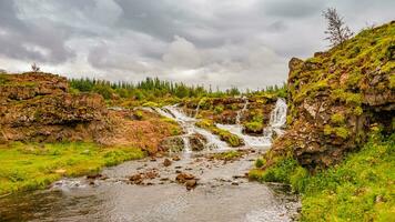 Maravilhoso Waterfal nomeado Kermoafoss dentro Islândia, dentro a cidade parque do reykjavík, dentro outono cores e dramático céu foto