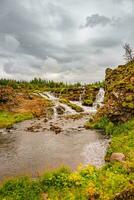 Maravilhoso cascata nomeado Kermoafoss dentro Islândia, dentro a cidade parque do reykjavík, dentro outono cores e dramático pôr do sol céu foto