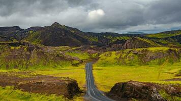 panorâmico pássaro Visão sobre uma pavimentou estrada e dramático islandês colorida e selvagem panorama às verão tempo, Islândia foto
