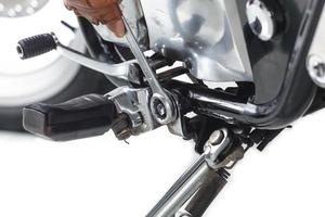 vista recortada do mecânico usando uma chave inglesa em uma motocicleta em fundo branco