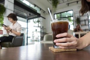 feche a mão de uma mulher segurando um café gelado em uma cafeteria foto