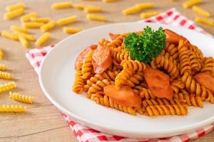 macarrão espiral ou espiral com molho de tomate e salsicha - comida italiana foto