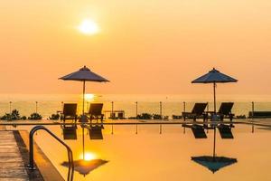 lindo guarda-sol e cadeira ao redor da piscina no hotel e resort foto