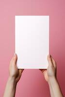 uma humano mão segurando uma em branco Folha do branco papel ou cartão isolado em Rosa fundo. ai gerado foto