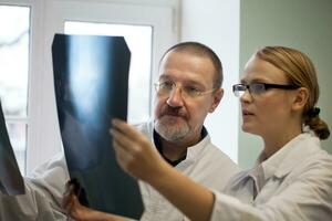 Senior e jovem médicos examinando raio X imagens foto