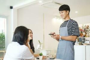 sorridente garçom levar ordem conversa para clientes cafeteria restaurante visitantes servindo funcionários Boa cliente serviço. foto