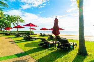 guarda-sóis e cadeiras de praia vermelhos com fundo de praia do mar e céu azul e luz do sol foto