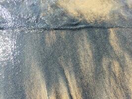 de praia molhado areia textura. arenoso costa bege fundo. foto