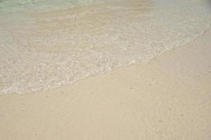 linda onda suave na areia no mar dia de sol foto