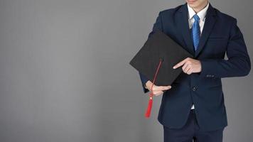 homem de negócios está segurando um chapéu de formatura, conceito de educação empresarial foto