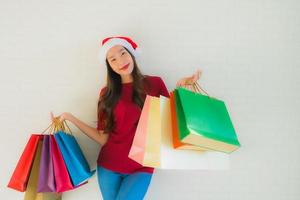 retrato lindas jovens mulheres asiáticas usam chapéu de Papai Noel de natal com sacola de compras foto