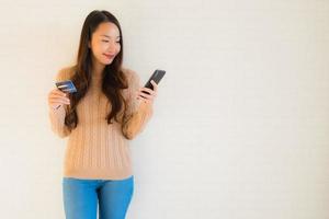retrato lindo jovem asiático usar telefone celular inteligente com cartão de crédito foto