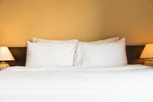 travesseiro branco confortável na cama com abajur foto