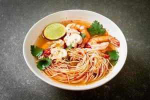 macarrão com sopa picante e camarão em tigela branca ou tom yum kung - comida asiática foto