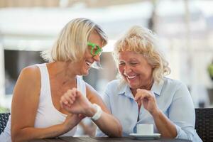 Senior mulheres rindo dentro rua cafeteria foto