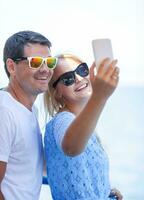 alegre casal dentro oculos de sol levando Móvel selfie foto