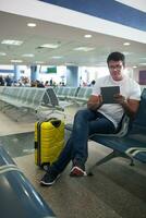 jovem homem usando toque almofada dentro a aeroporto salão foto