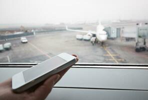 mão com inteligente telefone de a janela às aeroporto foto