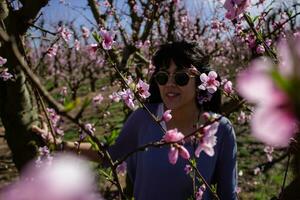 mulher entre a bonita Rosa pêssego árvore flores foto