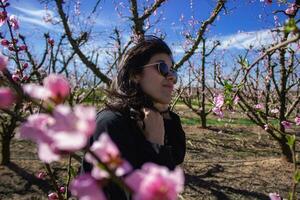 mulher entre a bonita Rosa pêssego árvore flores foto