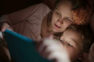 mãe e filho com almofada dentro cama às noite foto