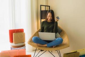 retrato de belas jovens mulheres asiáticas usando computador, laptop ou smartphone e celular com cartão de crédito para fazer compras online foto