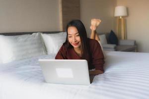 retrato de belas jovens mulheres asiáticas usando computador e telefone celular na cama
