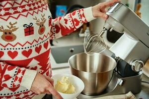 mulher cozinhando às casa cozinha, usar elétrico misturador para preparando massa foto