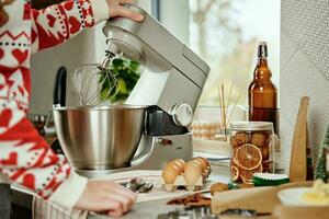 mulher cozinhando às casa cozinha, usar elétrico misturador para preparando massa foto