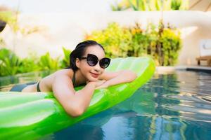 retrato bela jovem asiática sorrir feliz relaxe e lazer na piscina foto