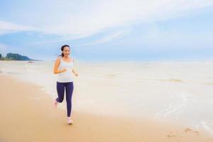 retrato bela jovem esporte mulher asiática exercício correndo e correndo na praia e no mar ao ar livre foto