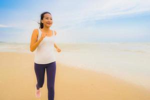 retrato bela jovem esporte mulher asiática exercício correndo e correndo na praia e no mar ao ar livre foto