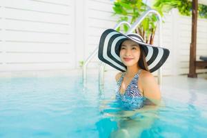 retrato linda jovem asiática feliz sorrindo relaxando na piscina ao ar livre foto
