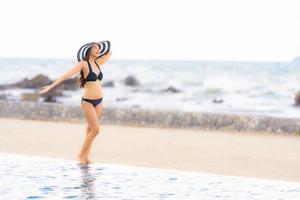 retrato bela jovem asiática usar biquíni ao redor da piscina em hotel resort perto do mar oceano praia foto