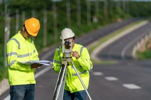 dois agrimensor engenheiros com equipamento em estrada construção site, Civil engenheiros, agrimensor equipamento. foto
