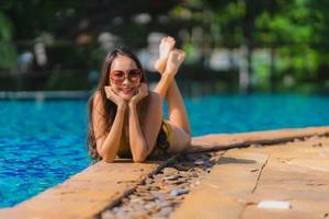 retrato linda jovem mulher asiática lazer relaxar sorriso e felicidade ao redor da piscina em hotel resort foto