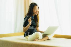 retrato bela jovem asiática usando computador notebook ou laptop com cartão de crédito para fazer compras foto