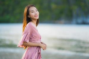 retrato jovem linda mulher asiática andar sorrindo e feliz na praia, mar e oceano foto