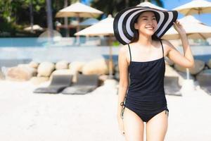 retrato linda jovem asiática feliz e sorridente na praia e no mar foto