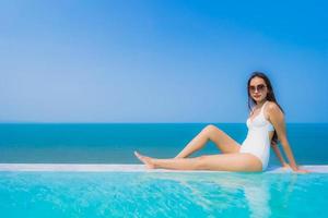 retrato bela jovem asiática feliz sorriso relaxar na piscina para viagens de férias foto