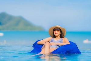 retrato bela jovem asiática feliz sorriso relaxar na piscina do hotel resort neary mar oceano praia no céu azul foto